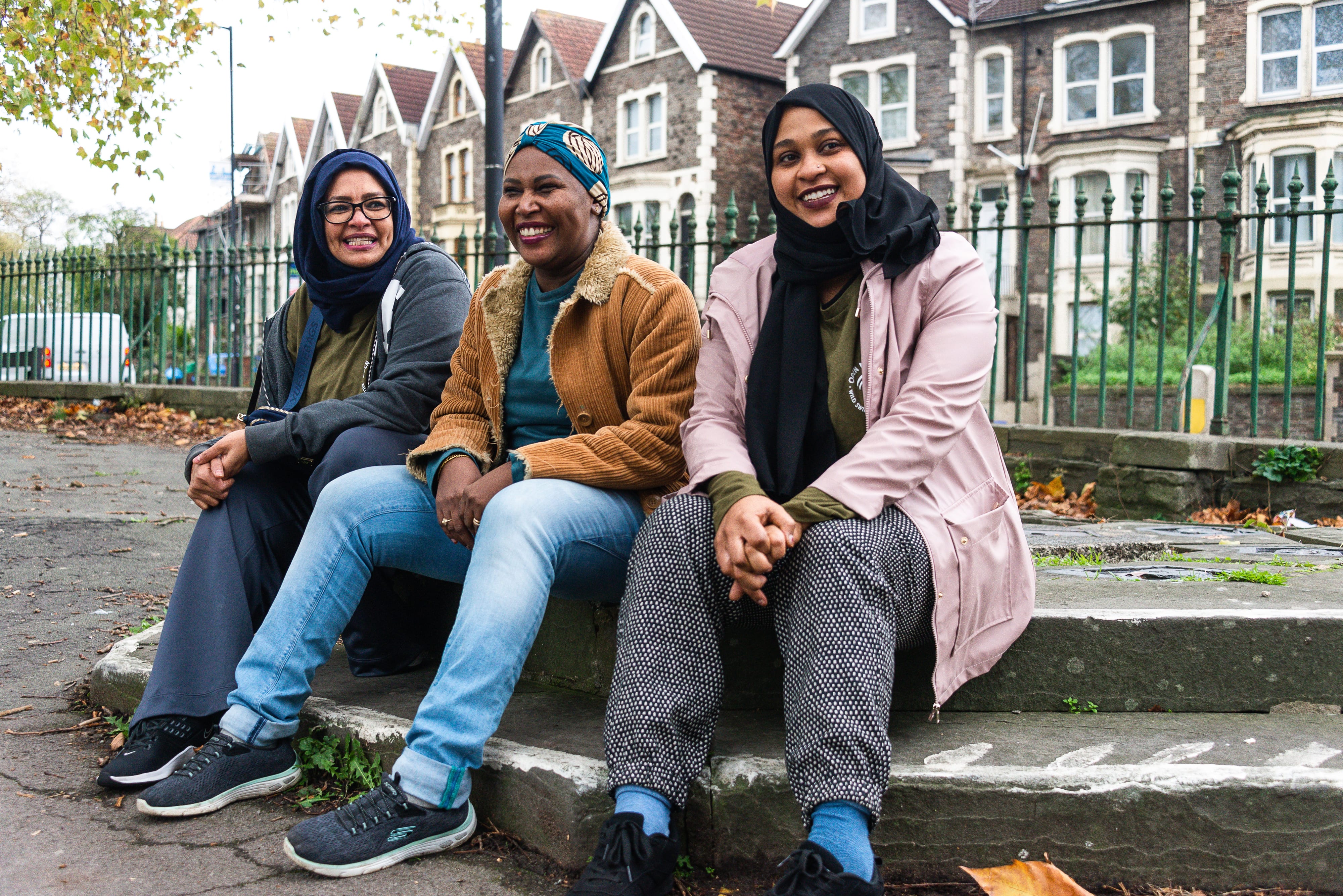 Three women sitting on a step and smiling.