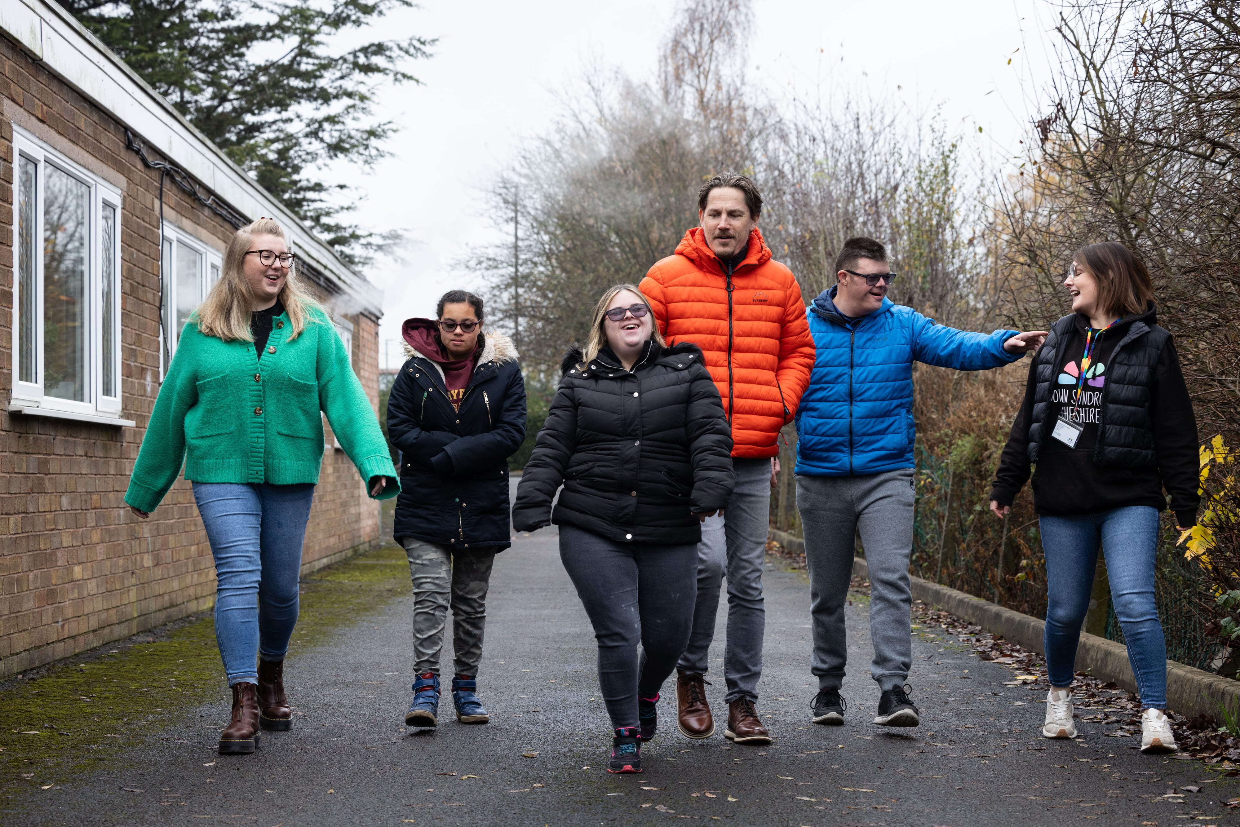 Six people talking and smiling while walking outside