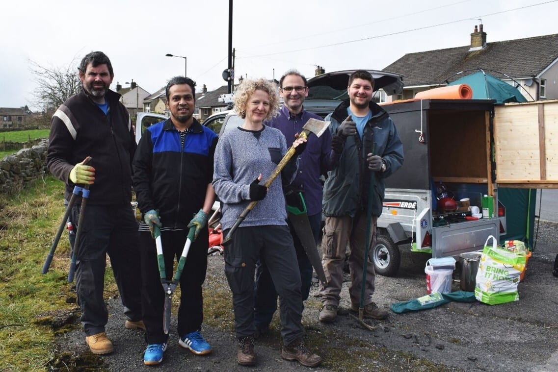 5 people stand with tools in a garden