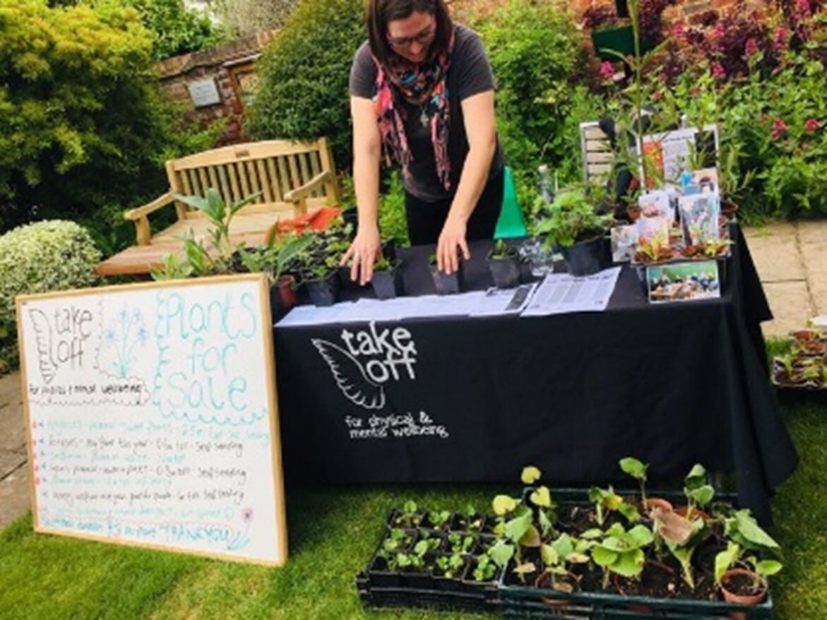 Person stands behind stall showing community garden project