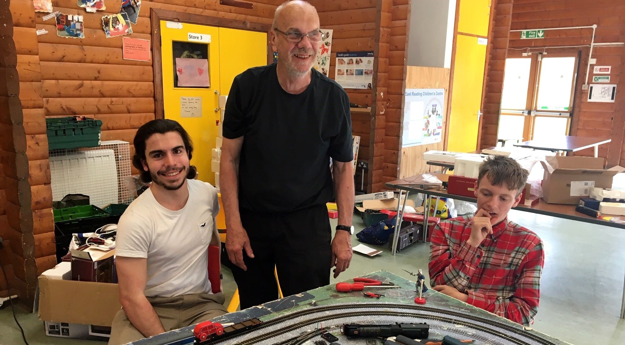 Three project participants sit around a train set at The Engine Shed