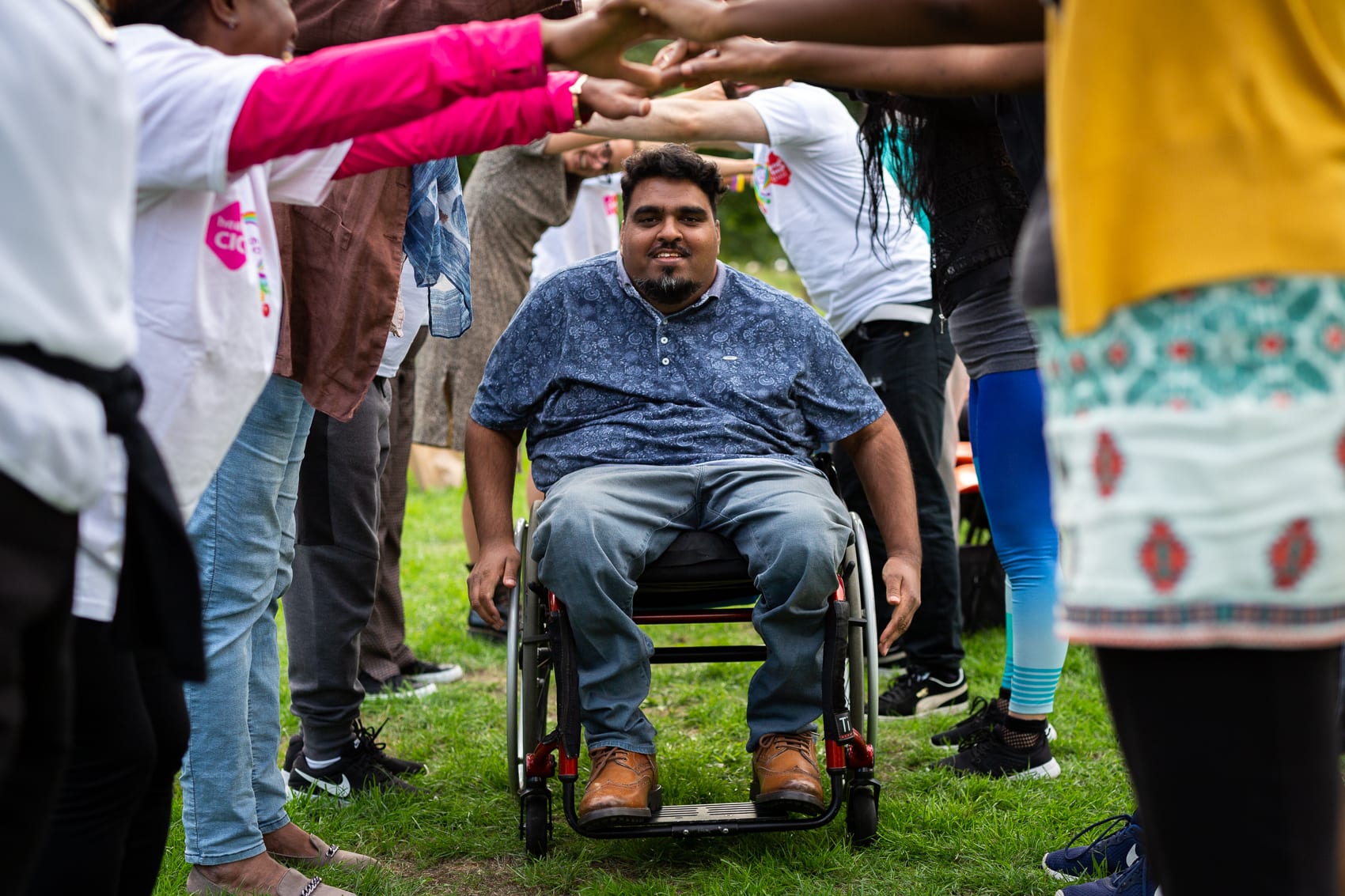 Person in wheelchair under people's arms